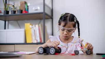 Asian students learn at home by coding robot cars and electronic board cables in STEM, STEAM, mathematics engineering science technology computer code in robotics for kids' concepts. photo