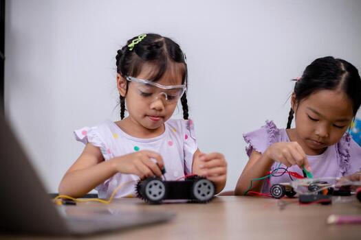 Asian students learn at home by coding robot cars and electronic board cables in STEM, STEAM, mathematics engineering science technology computer code in robotics for kids' concepts. photo