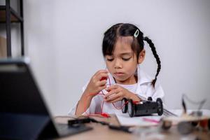 Asian students learn at home by coding robot cars and electronic board cables in STEM, STEAM, mathematics engineering science technology computer code in robotics for kids' concepts. photo