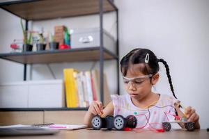 Asian students learn at home by coding robot cars and electronic board cables in STEM, STEAM, mathematics engineering science technology computer code in robotics for kids' concepts. photo