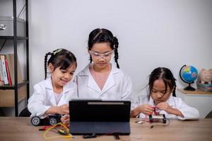 los estudiantes asiáticos aprenden en casa codificando automóviles robot y cables de placas electrónicas en tallo, vapor, ingeniería matemática, ciencia, tecnología, código informático en robótica para conceptos infantiles. foto