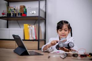 Asian students learn at home by coding robot cars and electronic board cables in STEM, STEAM, mathematics engineering science technology computer code in robotics for kids' concepts. photo