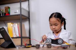 Asian students learn at home by coding robot cars and electronic board cables in STEM, STEAM, mathematics engineering science technology computer code in robotics for kids' concepts. photo