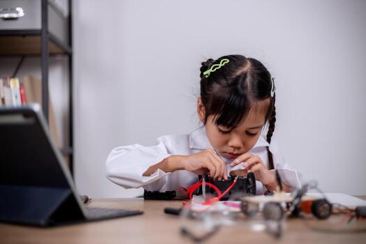 Asian students learn at home by coding robot cars and electronic board cables in STEM, STEAM, mathematics engineering science technology computer code in robotics for kids' concepts. photo