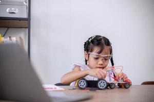 los estudiantes asiáticos aprenden en casa codificando automóviles robot y cables de placas electrónicas en tallo, vapor, ingeniería matemática, ciencia, tecnología, código informático en robótica para conceptos infantiles. foto