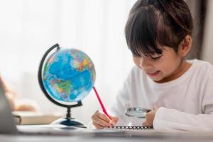 Asian little girl is learning the globe model, concept of save the world and learn through play activity for kid education at home. photo