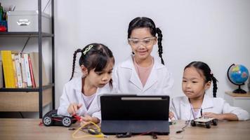 los estudiantes asiáticos aprenden en casa codificando automóviles robot y cables de placas electrónicas en tallo, vapor, ingeniería matemática, ciencia, tecnología, código informático en robótica para conceptos infantiles. foto