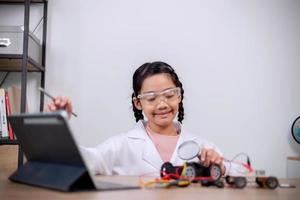 los estudiantes asiáticos aprenden en casa codificando automóviles robot y cables de placas electrónicas en tallo, vapor, ingeniería matemática, ciencia, tecnología, código informático en robótica para conceptos infantiles. foto