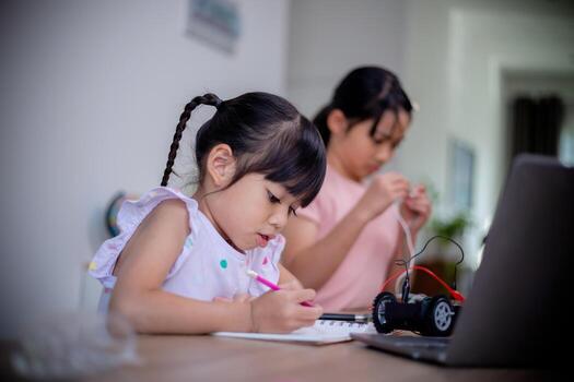 Asian students learn at home by coding robot cars and electronic board cables in STEM, STEAM, mathematics engineering science technology computer code in robotics for kids' concepts. photo