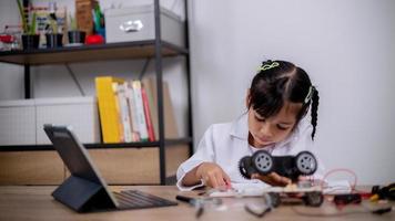 Asian students learn at home by coding robot cars and electronic board cables in STEM, STEAM, mathematics engineering science technology computer code in robotics for kids' concepts. photo