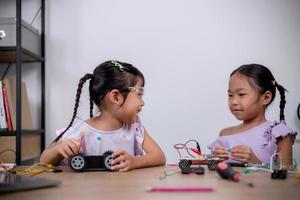 los estudiantes asiáticos aprenden en casa codificando automóviles robot y cables de placas electrónicas en tallo, vapor, ingeniería matemática, ciencia, tecnología, código informático en robótica para conceptos infantiles. foto