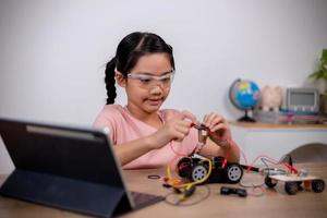 Asian students learn at home by coding robot cars and electronic board cables in STEM, STEAM, mathematics engineering science technology computer code in robotics for kids' concepts. photo