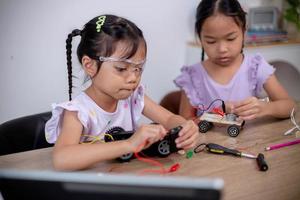 los estudiantes asiáticos aprenden en casa codificando automóviles robot y cables de placas electrónicas en tallo, vapor, ingeniería matemática, ciencia, tecnología, código informático en robótica para conceptos infantiles. foto