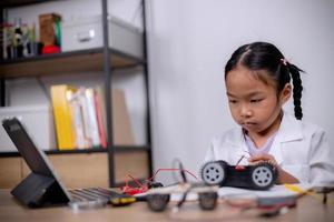 Asian students learn at home by coding robot cars and electronic board cables in STEM, STEAM, mathematics engineering science technology computer code in robotics for kids' concepts. photo