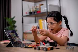 Asian students learn at home by coding robot cars and electronic board cables in STEM, STEAM, mathematics engineering science technology computer code in robotics for kids' concepts. photo