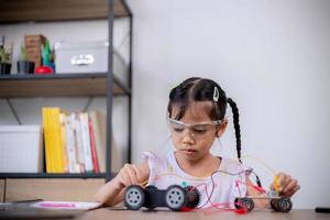 Asian students learn at home by coding robot cars and electronic board cables in STEM, STEAM, mathematics engineering science technology computer code in robotics for kids' concepts. photo