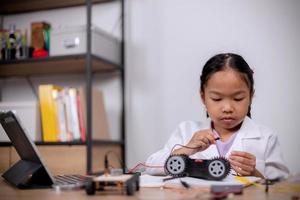 Asian students learn at home by coding robot cars and electronic board cables in STEM, STEAM, mathematics engineering science technology computer code in robotics for kids' concepts. photo