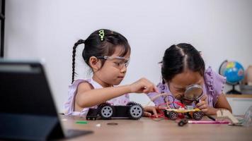 los estudiantes asiáticos aprenden en casa codificando automóviles robot y cables de placas electrónicas en tallo, vapor, ingeniería matemática, ciencia, tecnología, código informático en robótica para conceptos infantiles. foto