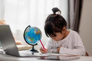 Asian little girl is learning the globe model, concept of save the world and learn through play activity for kid education at home. photo