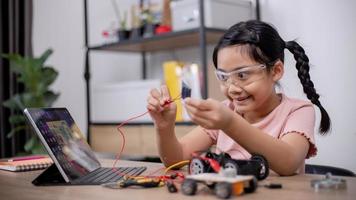 Asian students learn at home by coding robot cars and electronic board cables in STEM, STEAM, mathematics engineering science technology computer code in robotics for kids' concepts. photo
