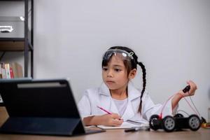 Asian students learn at home by coding robot cars and electronic board cables in STEM, STEAM, mathematics engineering science technology computer code in robotics for kids' concepts. photo