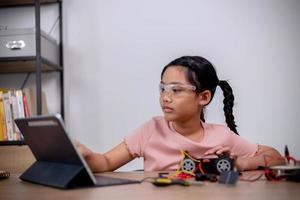 Asian students learn at home by coding robot cars and electronic board cables in STEM, STEAM, mathematics engineering science technology computer code in robotics for kids' concepts. photo