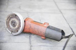 used electrical angle grinder on gray cement floor, famous construction hand tool machine photo