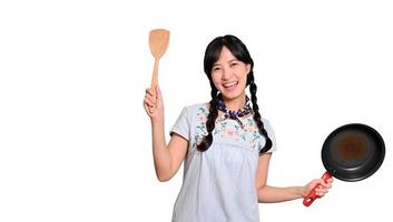 Portrait of beautiful young asian woman wear denim dress with black pan and spatula on white isolated background photo