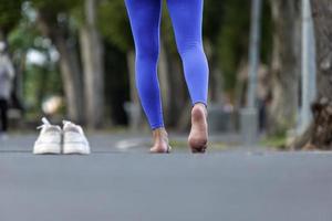 mujer corredora corre descalza sin zapatos para evitar juanetes, aquiles y otras lesiones en los pies como resultado de la puntera estrecha de los zapatos deportivos convencionales para construir un mejor concepto de fuerza muscular foto