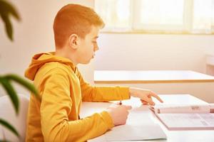 Teenage boy write homework at home. Education concept photo