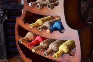 Colorful wine bottles wrapped in a rope on stand. Interior design element photo