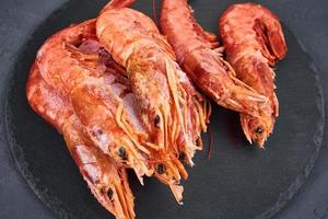 Frozen seafood. Fresh shrimps on dark background. Red raw prawns photo