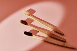 Reusable bamboo toothbrushes on pink background. Zero waste photo