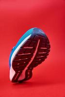 Blue running sneaker on red background, close up photo