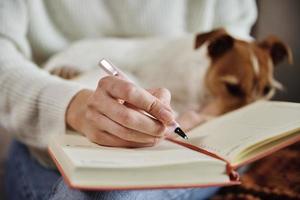 mujer escribe notas en un cuaderno en casa foto