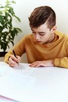 Teenage boy write homework at home. Education concept photo