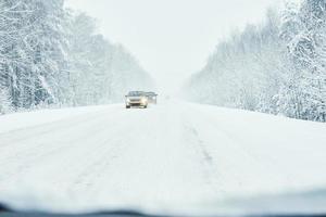 Snowy road in winter forest with moving car photo