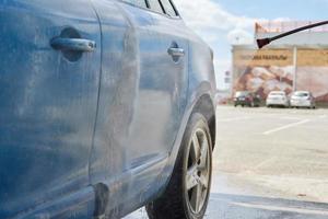 Cleaning car with high pressure water at car wash station photo