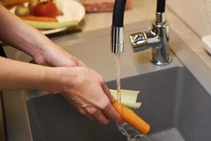 Woman wash fresh vegetable in kitchen photo