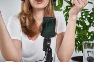 Woman recording online podcast at home. Microphone on table. home studio workplace photo