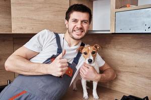 Worker man maintenance kitchen furniture with his dog photo