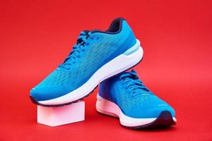 Pair of blue running sneakers on red background photo