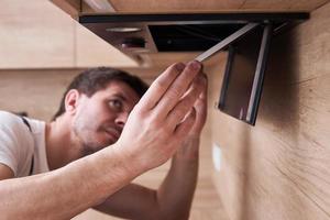 Man repairs hood in kitchen. Replacement filter in cooker hood photo
