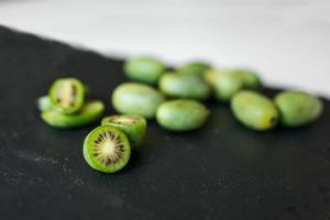 New Zealand exotic food. Berry nergi, or small kiwi. Grey stone background. Baby kiwi or mini kiwi fruits on stone background. Closeup view photo