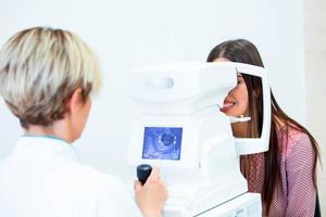 Female doctor ophthalmologist is checking the eye vision of attractive young woman in modern clinic. Doctor and patient in ophthalmology clinic. photo