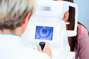 Female doctor ophthalmologist is checking the eye vision of attractive young woman in modern clinic. Doctor and patient in ophthalmology clinic. photo