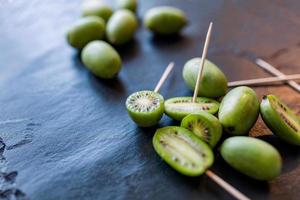 New Zealand exotic food. Berry nergi, or small kiwi. Grey stone background. Baby kiwi or mini kiwi fruits on stone background. Closeup view photo