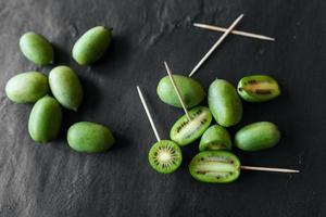 comida exótica de nueva zelanda. berry nergi, o kiwi pequeño. fondo de piedra gris. kiwi bebé o mini kiwis sobre fondo de piedra. vista de cerca foto