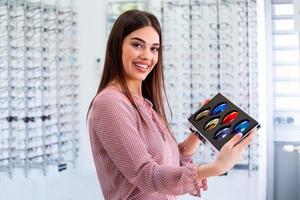 atractiva joven doctora en la clínica de oftalmología que muestra diferentes lentes polarizados foto