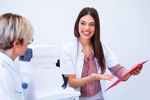 female ophthalmologist showing patient's data to a clipboard, working in an optical store. Healthcare and medicine concept photo